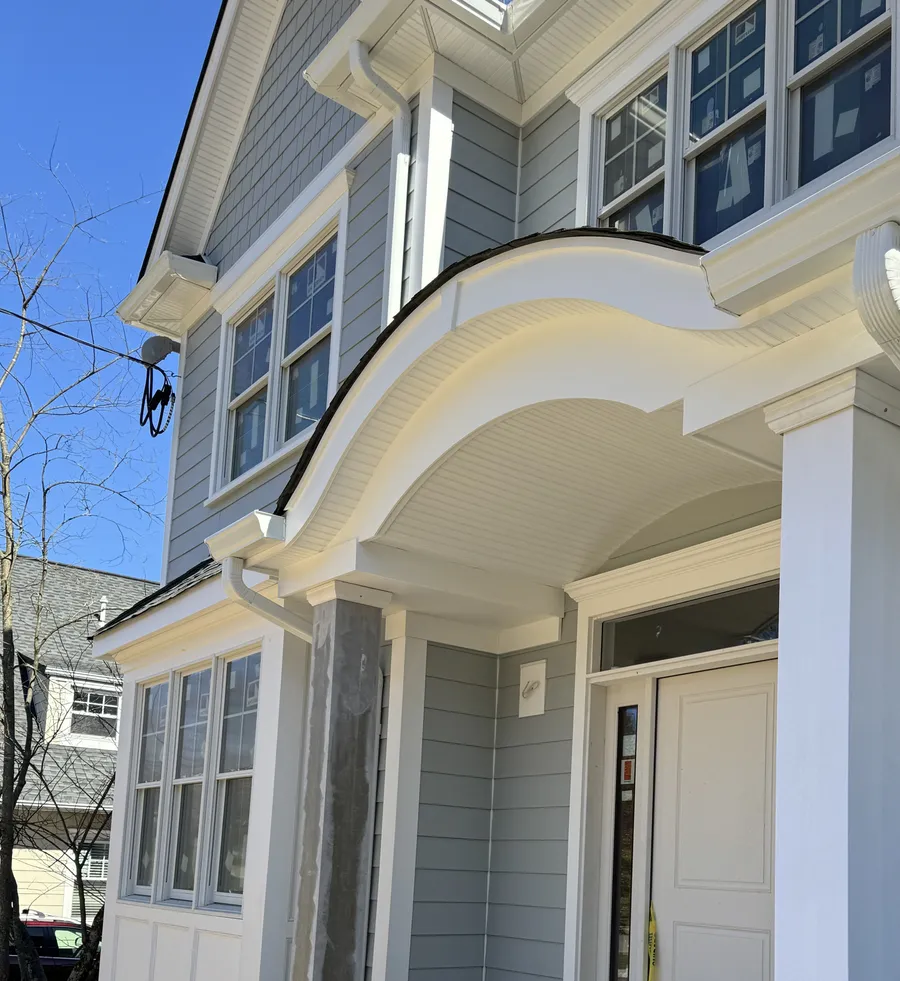 White scrolled entry portico with a fluted column and beadboard soffit by North Valley Exteriors