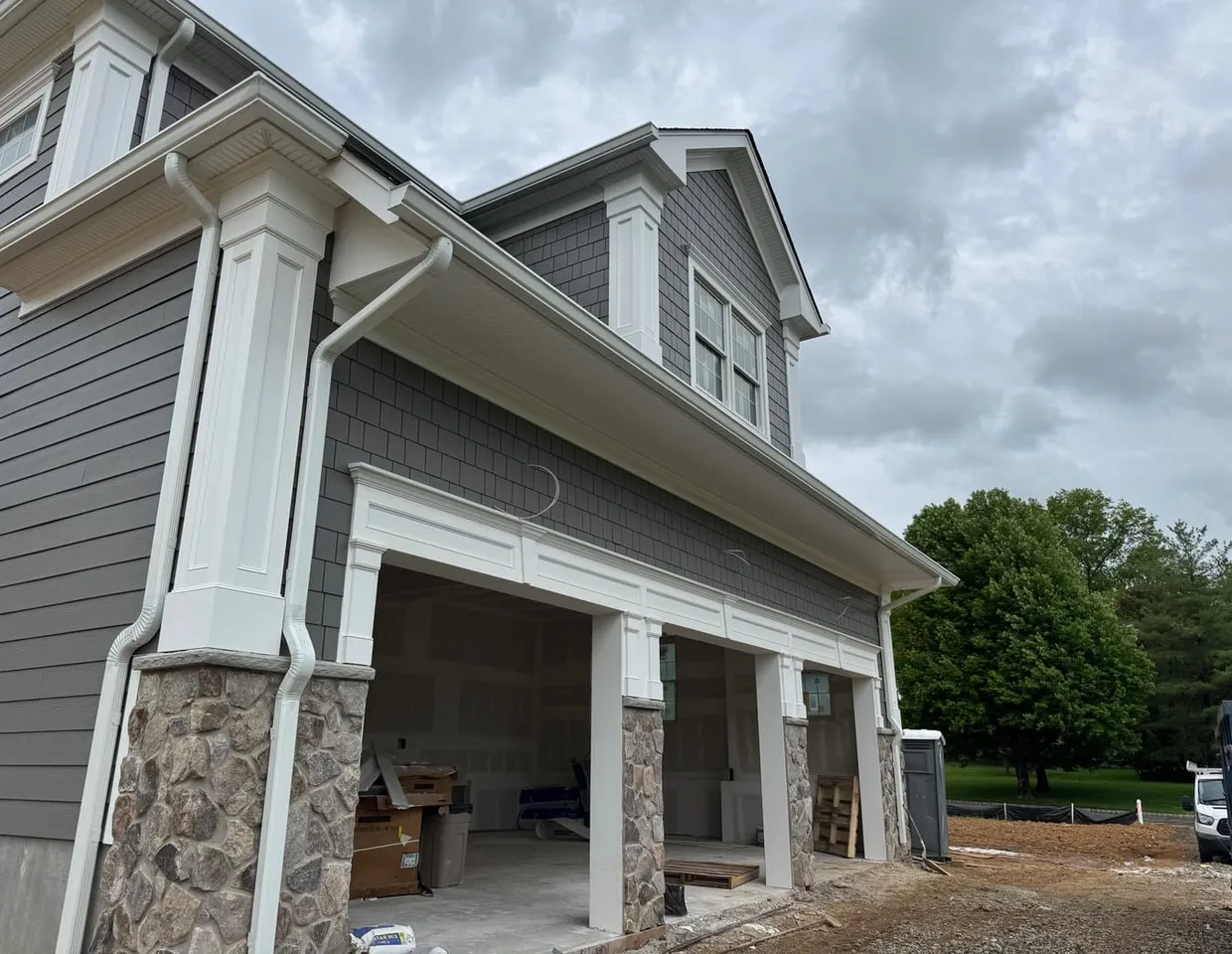 Clean white gutters and downspouts on a gray shake home by North Valley Exteriors