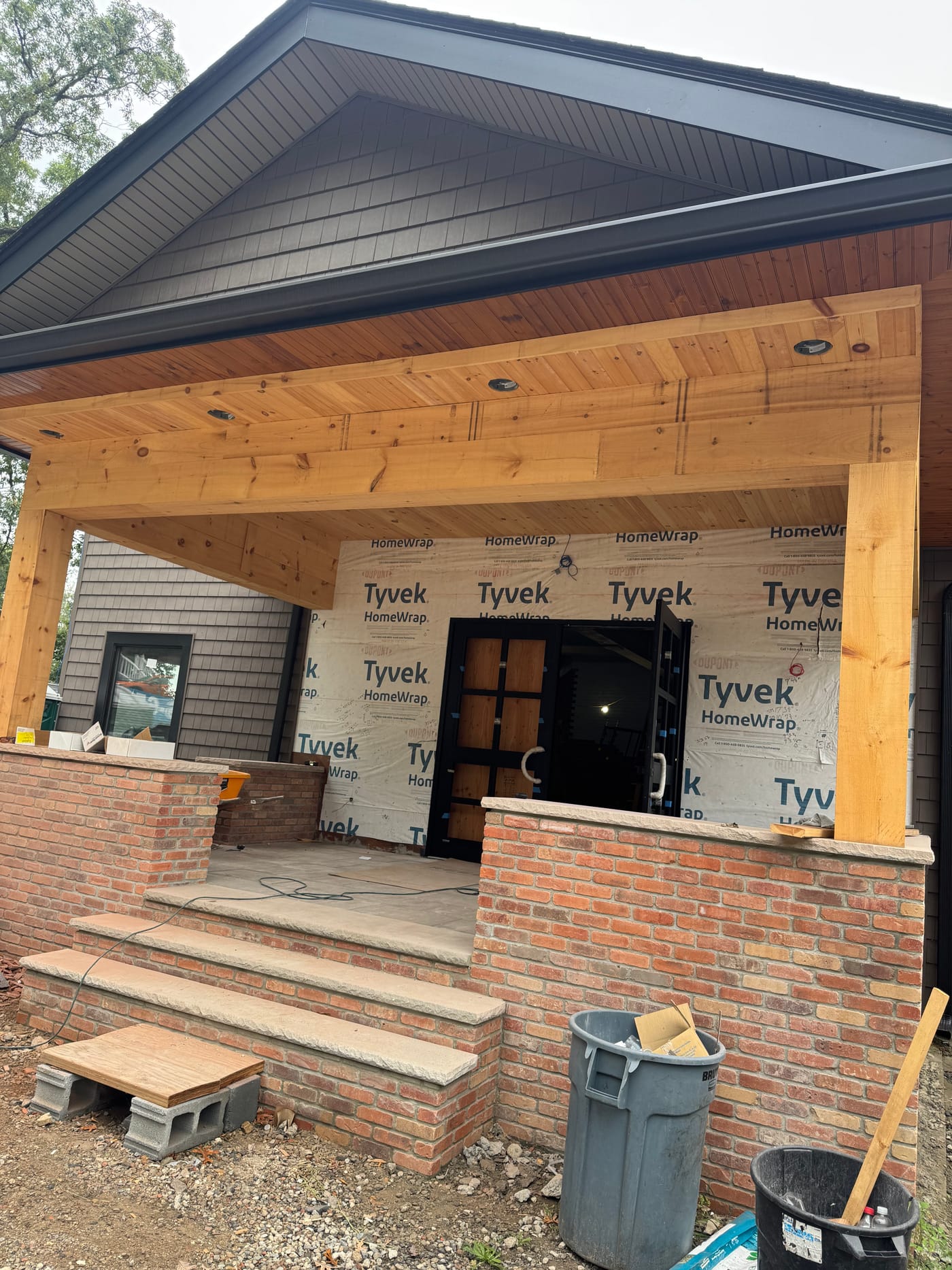 Cedar heavy-timber covered entry with a tongue-and-groove ceiling and brick knee walls