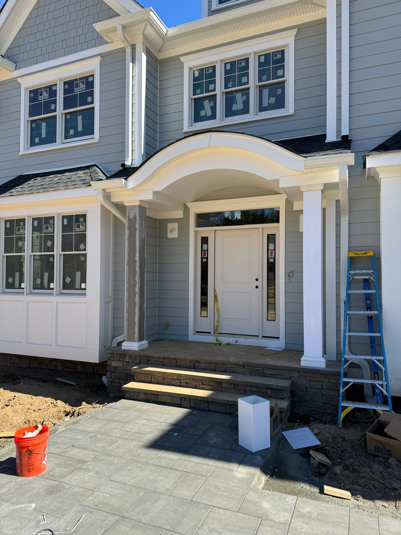 Entry with the white scroll portico hood over a dark fieldstone base