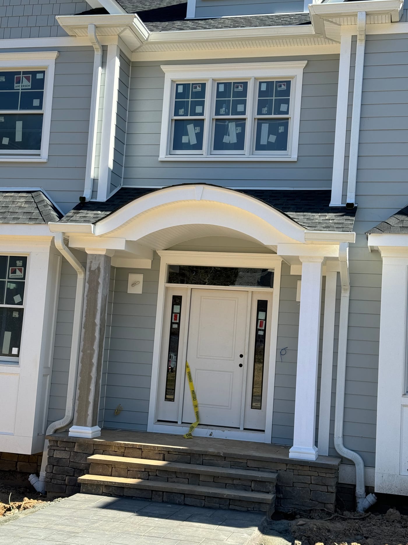 Wider view of the gray-blue vertical siding and scrolled entry