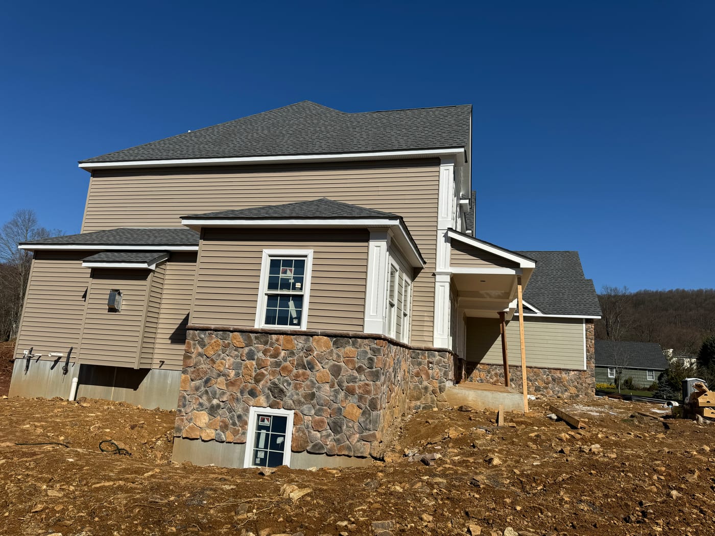 Side elevation with tan lap over a multicolor fieldstone wainscot