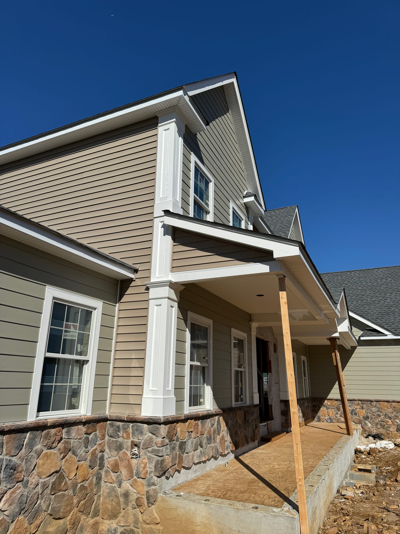 Gable ends in tan lap and sage board and batten siding