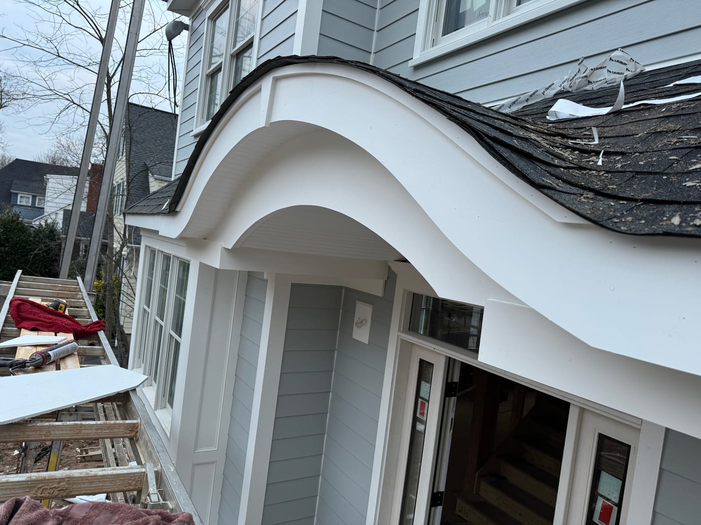 Finished curved AZEK eyebrow portico being shingled