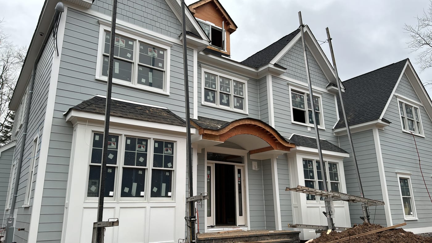 Near-finished blue-gray lap and shake front with the timber arch exposed