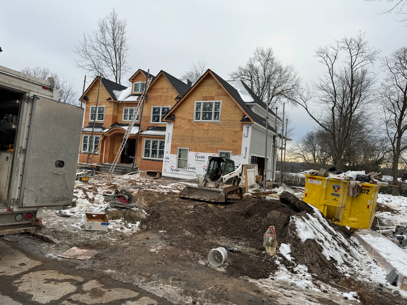 Winter jobsite with the home wrapped in house wrap and the arch framed