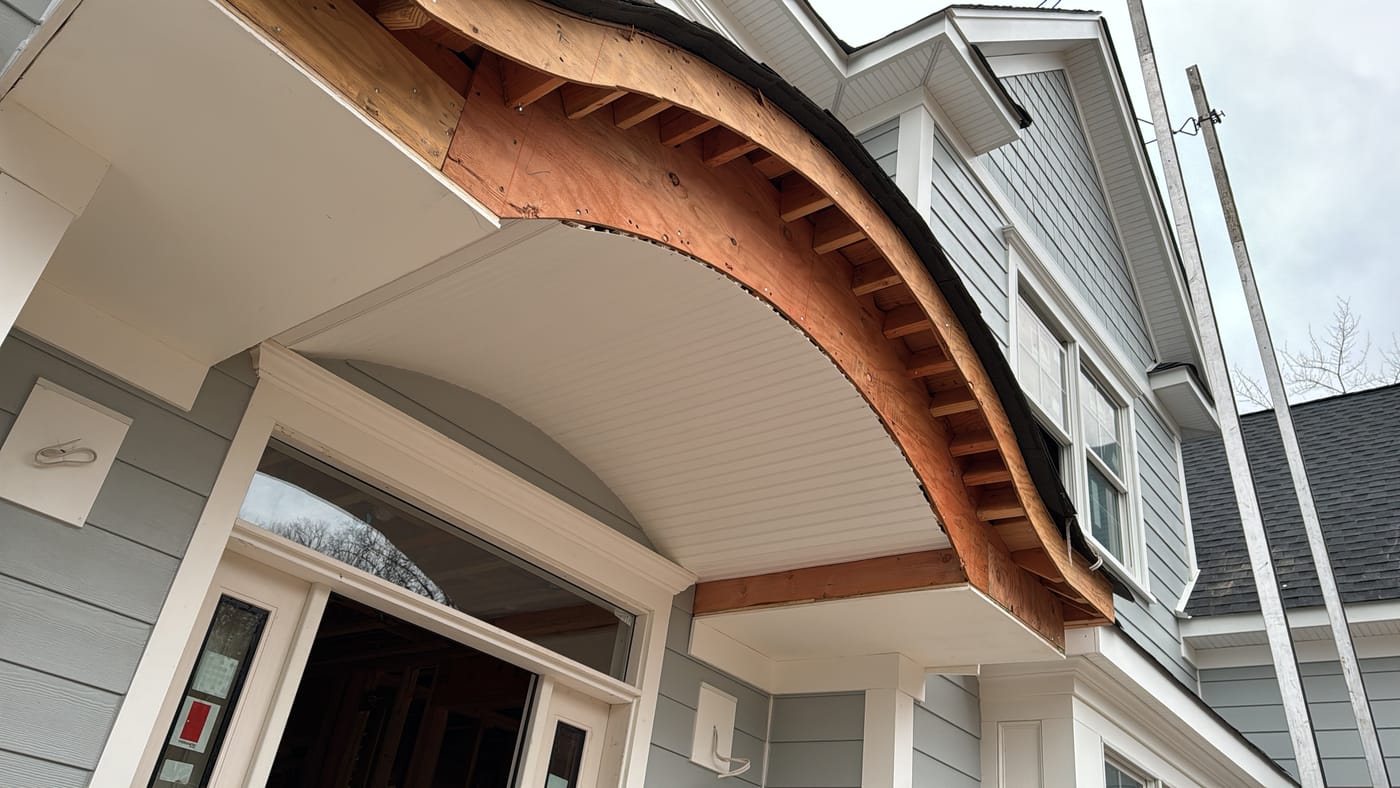 Curved eyebrow portico under construction with bent rafters