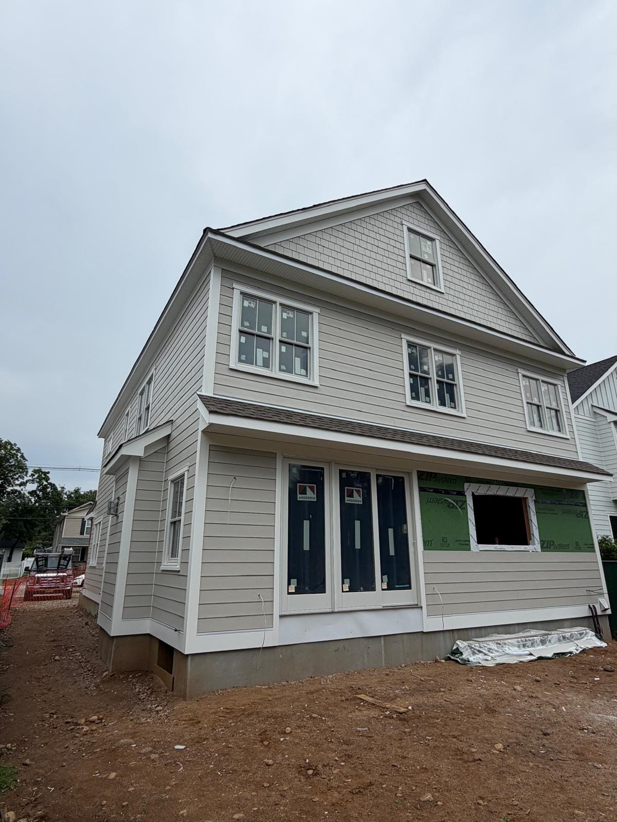 Near-finished greige gambrel home in shake and lap siding with white trim