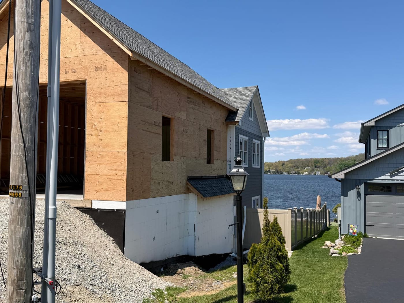 New garage wing in plywood sheathing beside the finished lakefront house