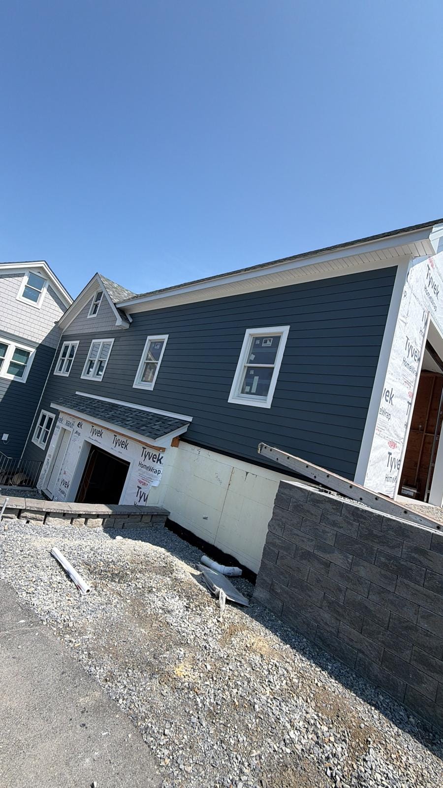Navy HardiePlank lap siding going on over the addition with white trim
