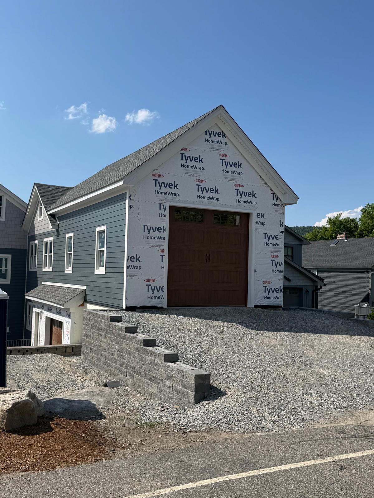 Detached garage wrapped in house wrap with a wood-look garage door