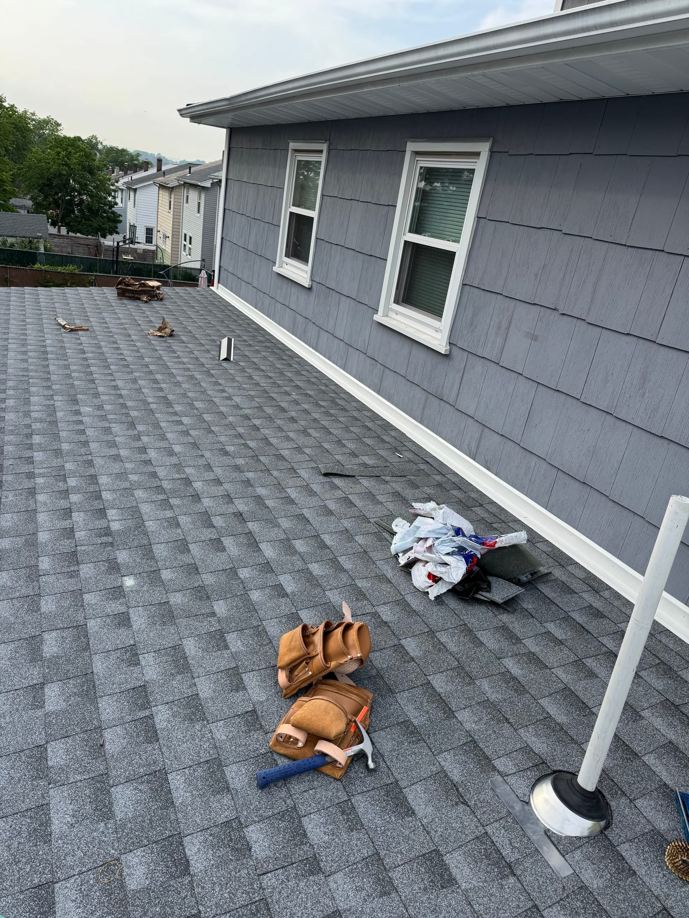 Architectural asphalt shingle roof field with new pipe-boot vent flashing and a gutter