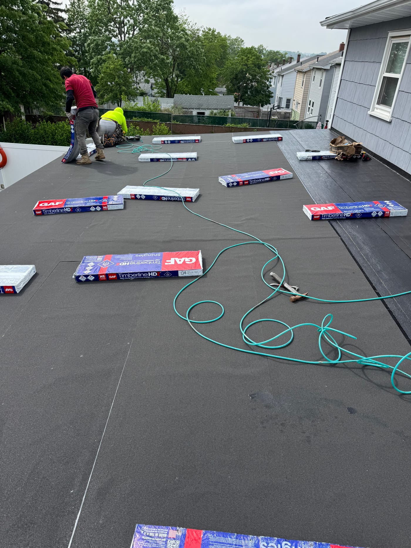 Low-slope roof section with GAF Timberline HDZ shingle bundles staged