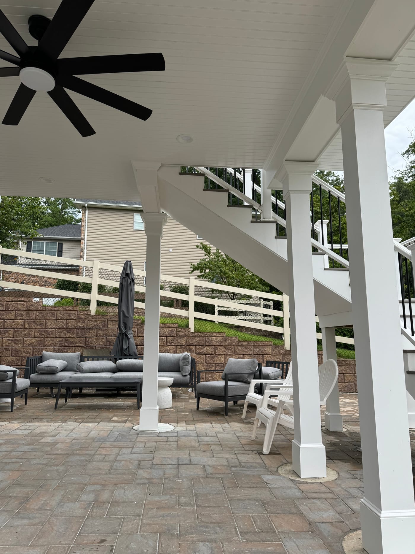Covered under-deck paver patio with white columns and a beadboard ceiling