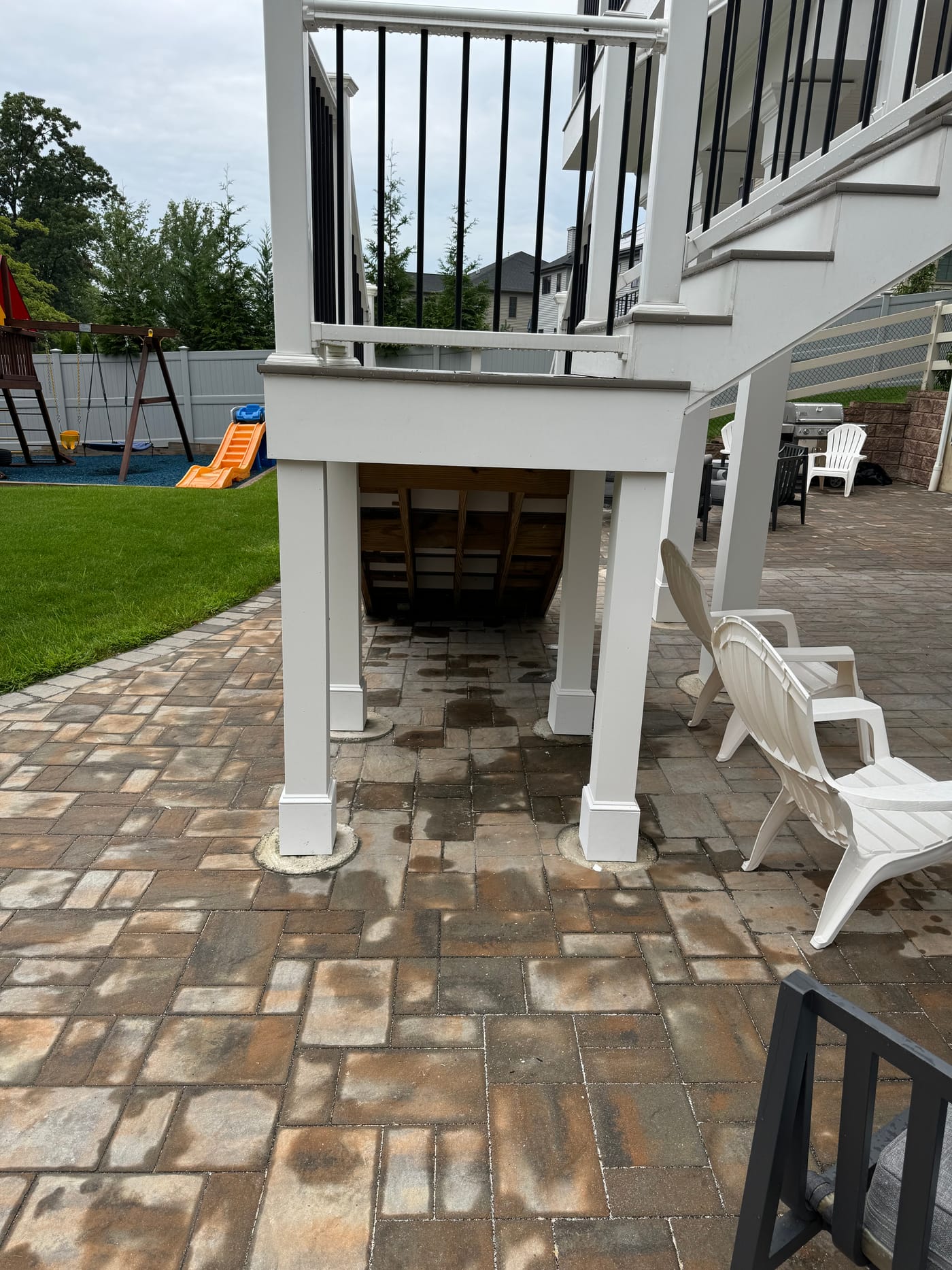 Paver patio with the deck stairs and the backyard beyond