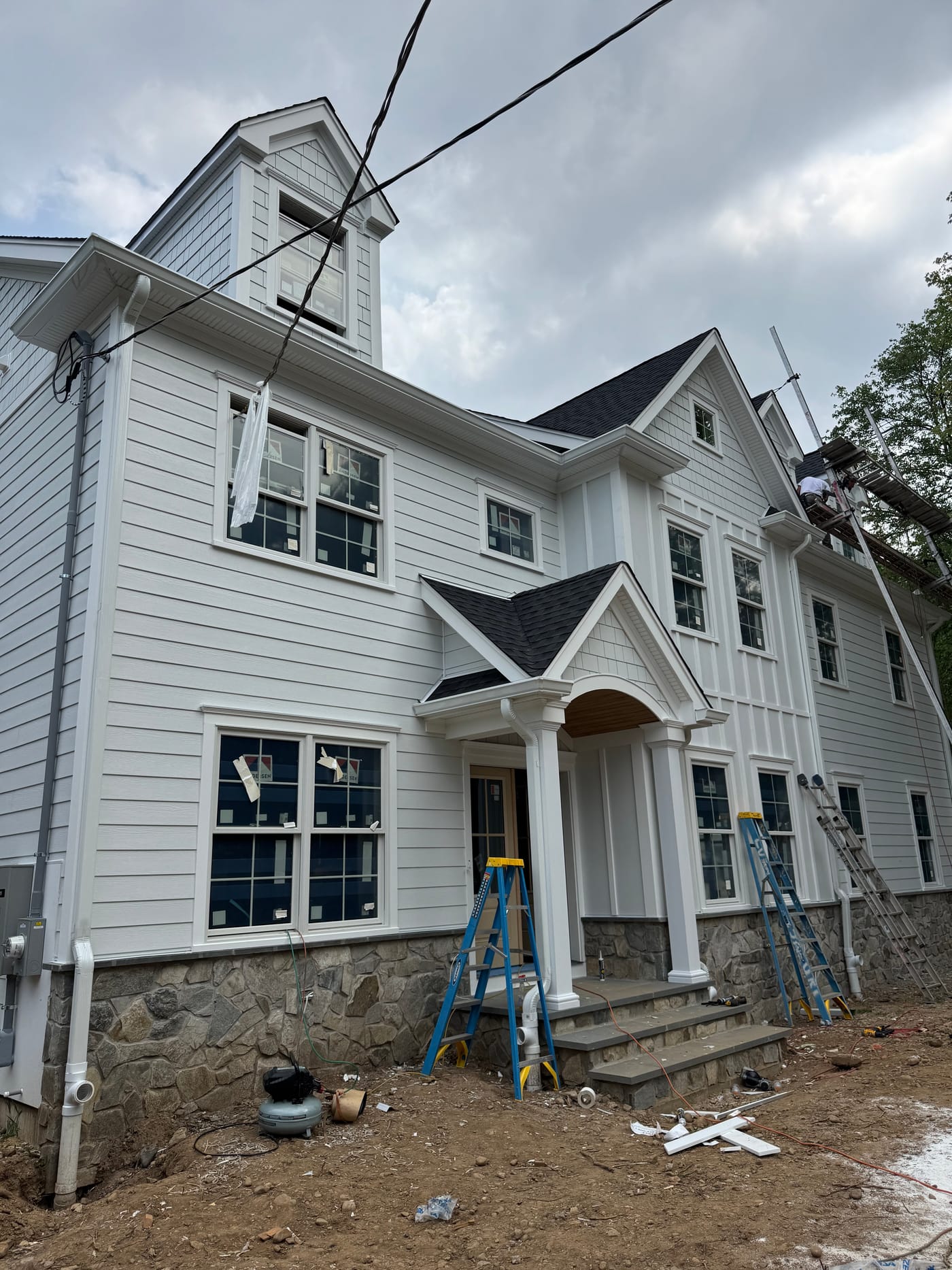 Three-quarter front of the white multi-texture farmhouse with a curved portico