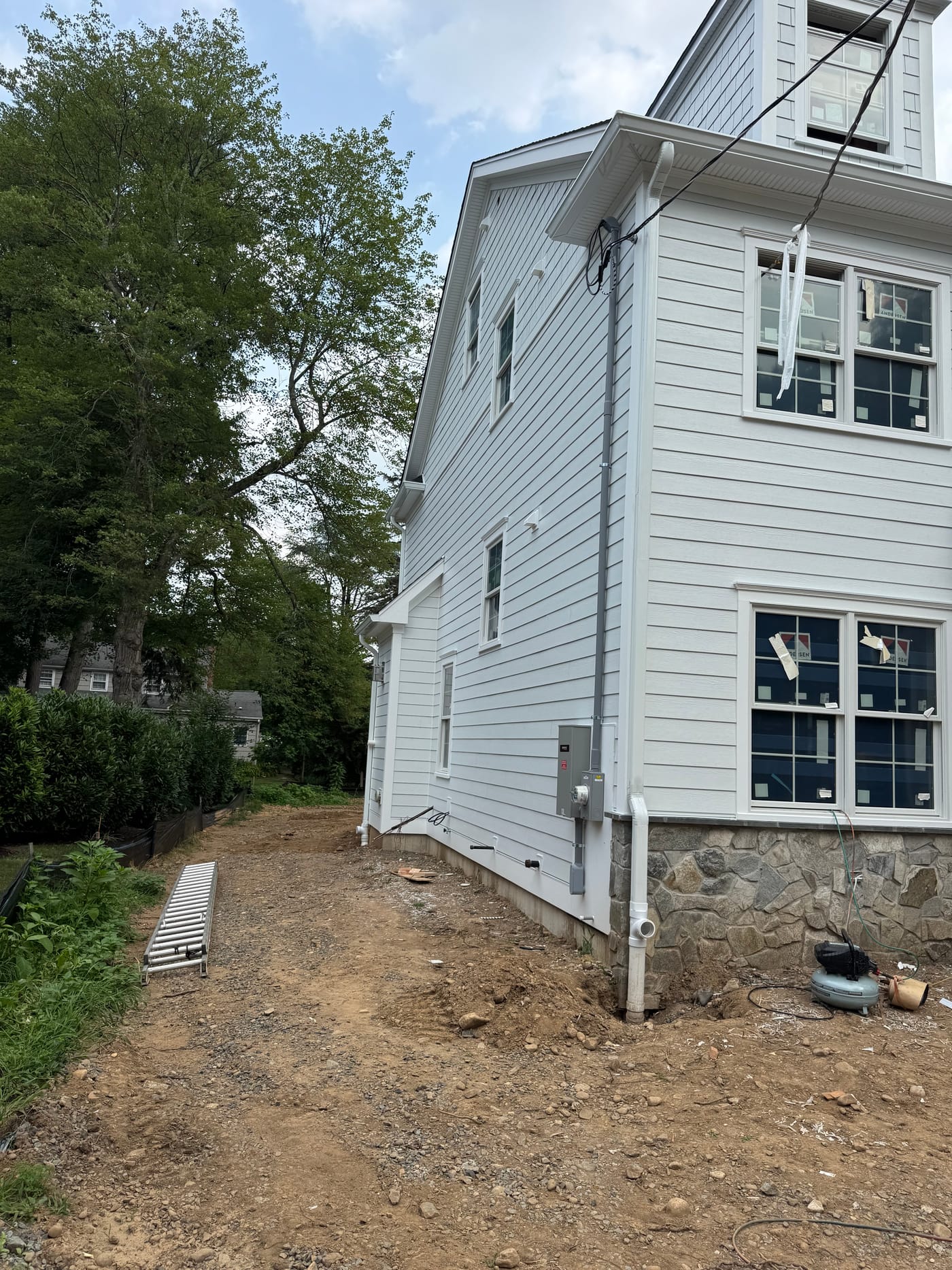Rear and side of the white home with beadboard porch soffit and a stone base