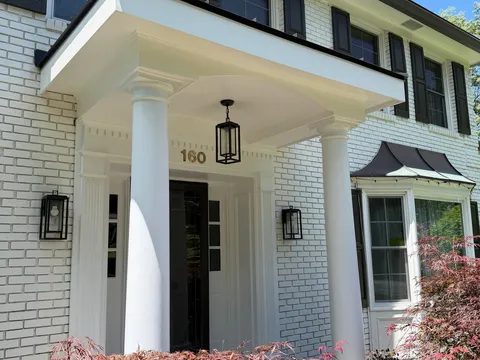 White brick colonial with a scrolled entry portico