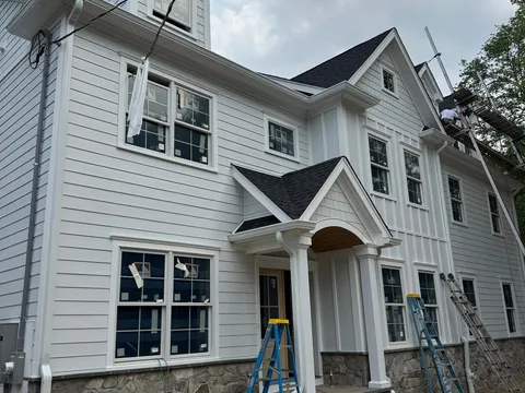 White multi-texture farmhouse with a curved portico
