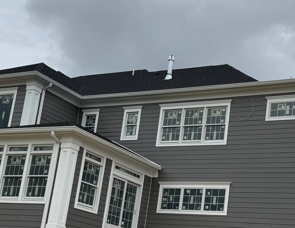 Rows of white-trimmed Andersen windows on a gray HardiePlank home by North Valley Exteriors